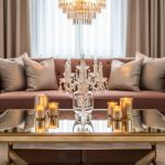 Glamour living room featuring a mirrored champagne-gold coffee table, dusty rose velvet seating, and crystal accents illuminated by warm candlelight.